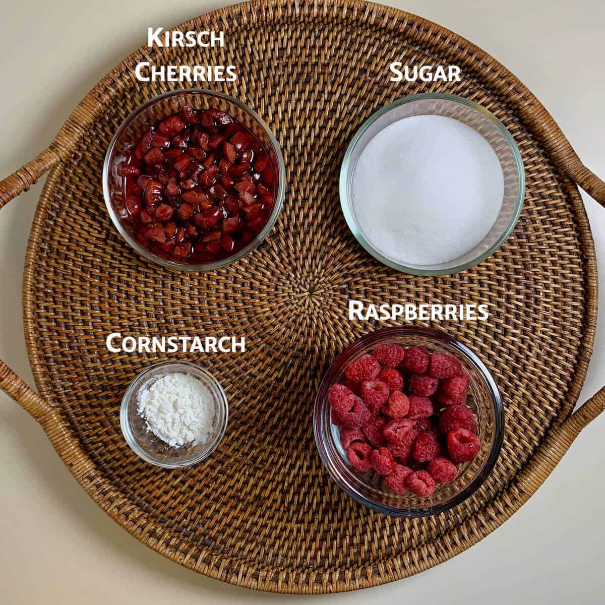 Raspberry & Kirsch cherry Jam ingredients on a wooden tray from overhead.