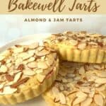 Three mini Bakewell tarts on a white cake stand Pinterest banner.