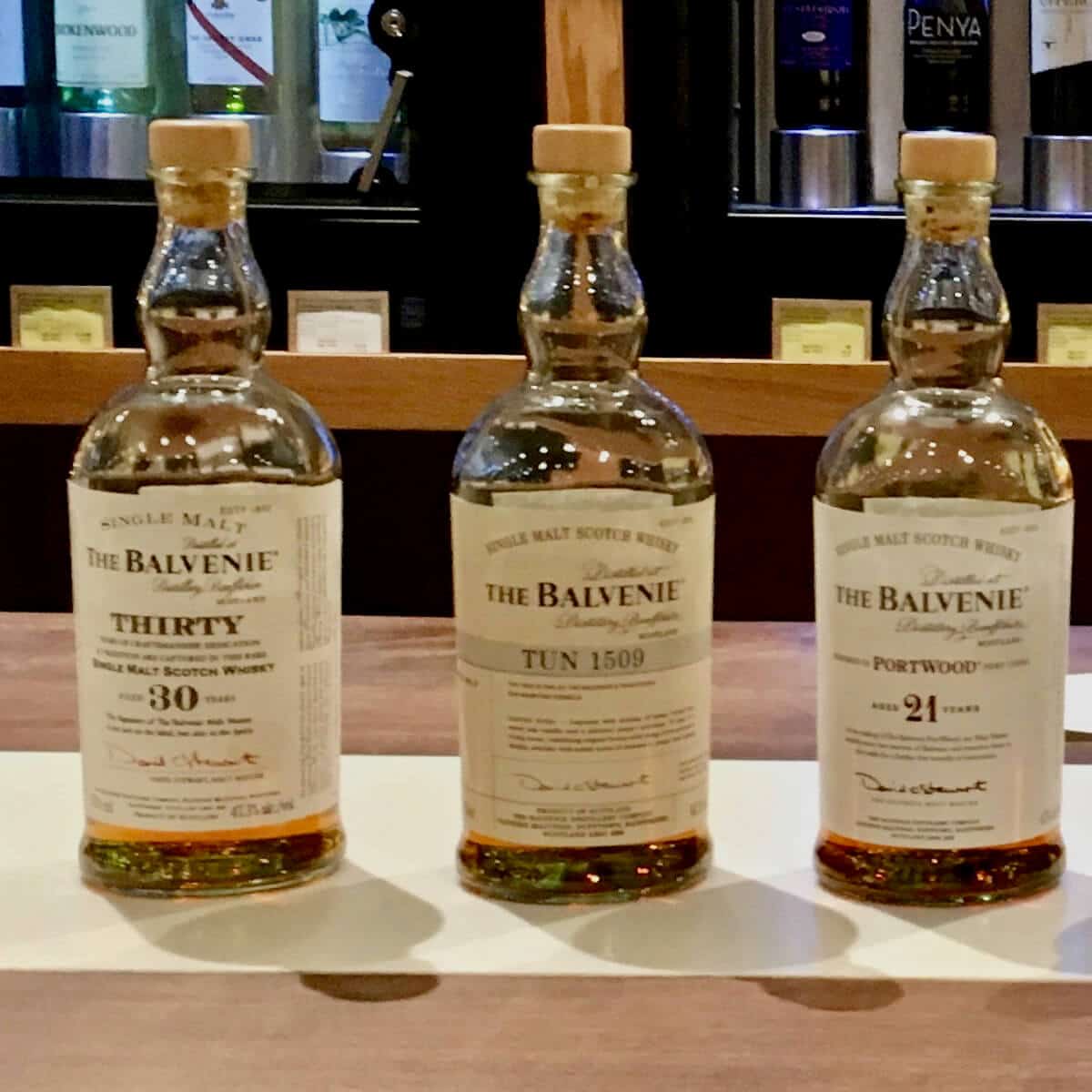 The Balvenie 21 year, Tun 1509, and 30 year lineup bottles on a counter.