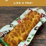 Eight strand braided challah in a napkin lined basket on a wood table Pinterest banner.