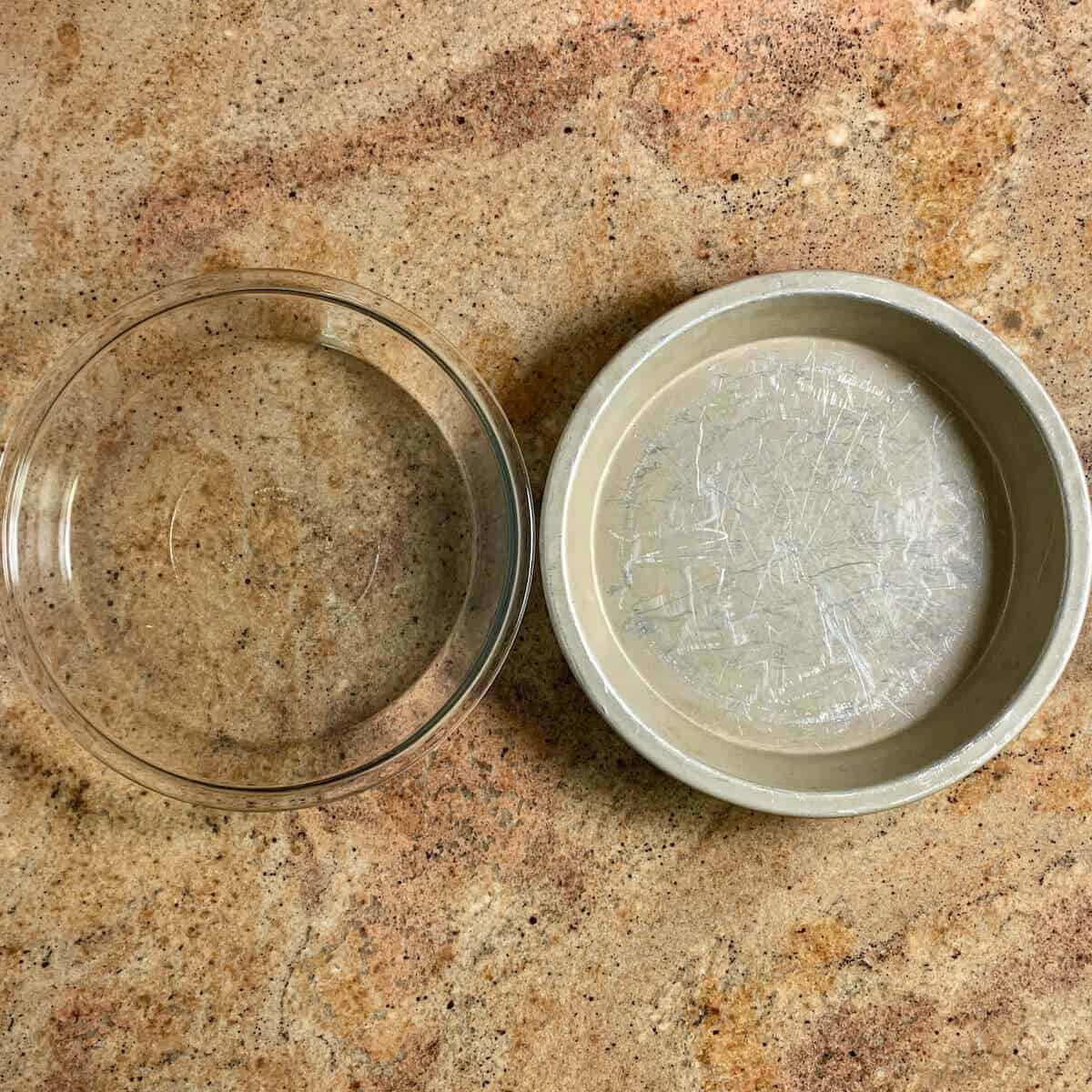 Two pie pans, glass and metal, sitting side by side.