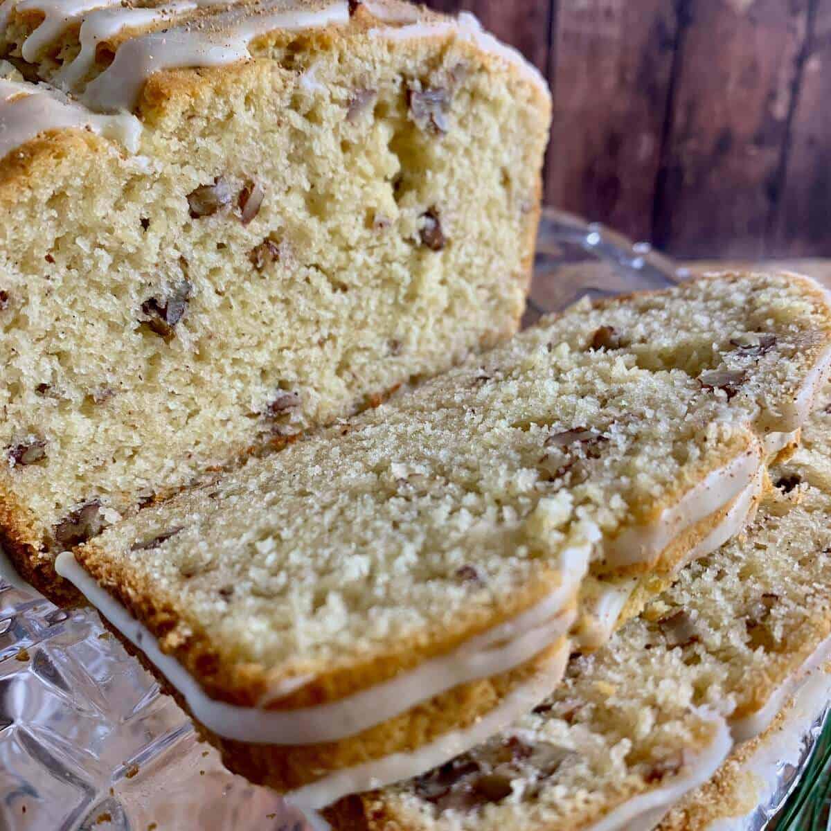 Closeup of sliced eggnog bread on a glass cake stand.