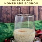 Glass of eggnog with pinecones on top of festive towels Pinterest banner.