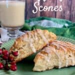 Two Eggnog Scones alongside red berries on a green plate with a mug of eggnog in the background Pinterest banner.