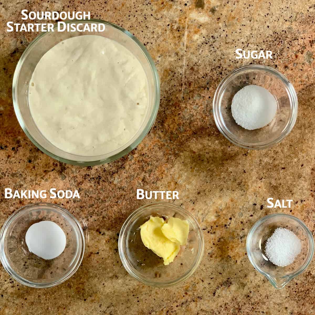 Ingredients for sourdough crumpets portioned in glass bowls from overhead.