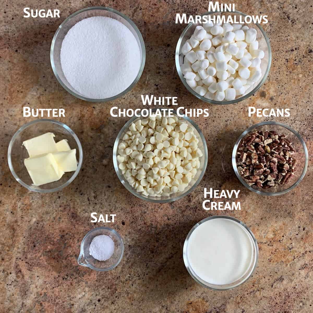 Ingredients for white chocolate pecan fudge portioned into glass bowls from overhead.