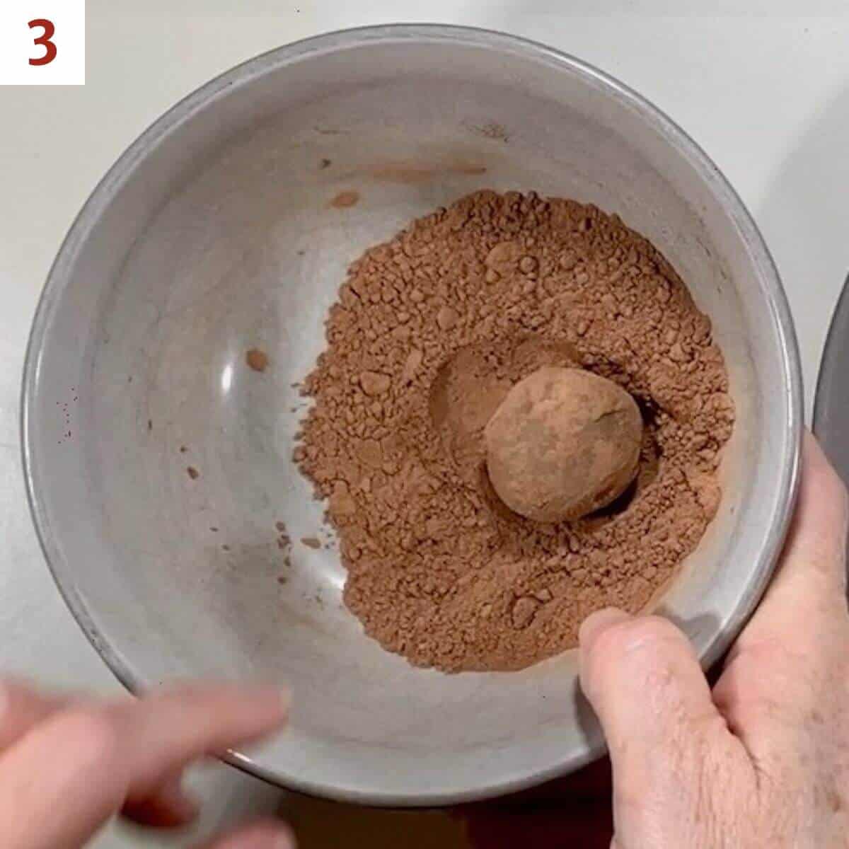 Rolling a truffle ball in cocoa powder.