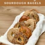 Assorted sourdough bagels on a white towel in a basket Pinterest banner..