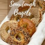 Assorted sourdough bagels on a white towel in a basket Pinterest banner..