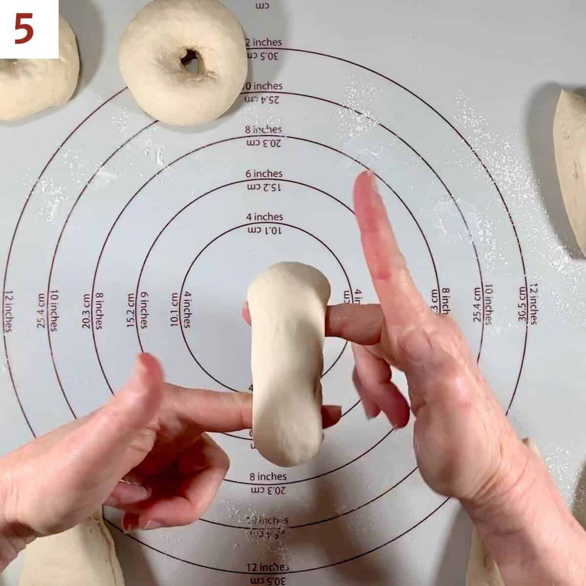 Demonstrating enlarging the hole in bagel dough.