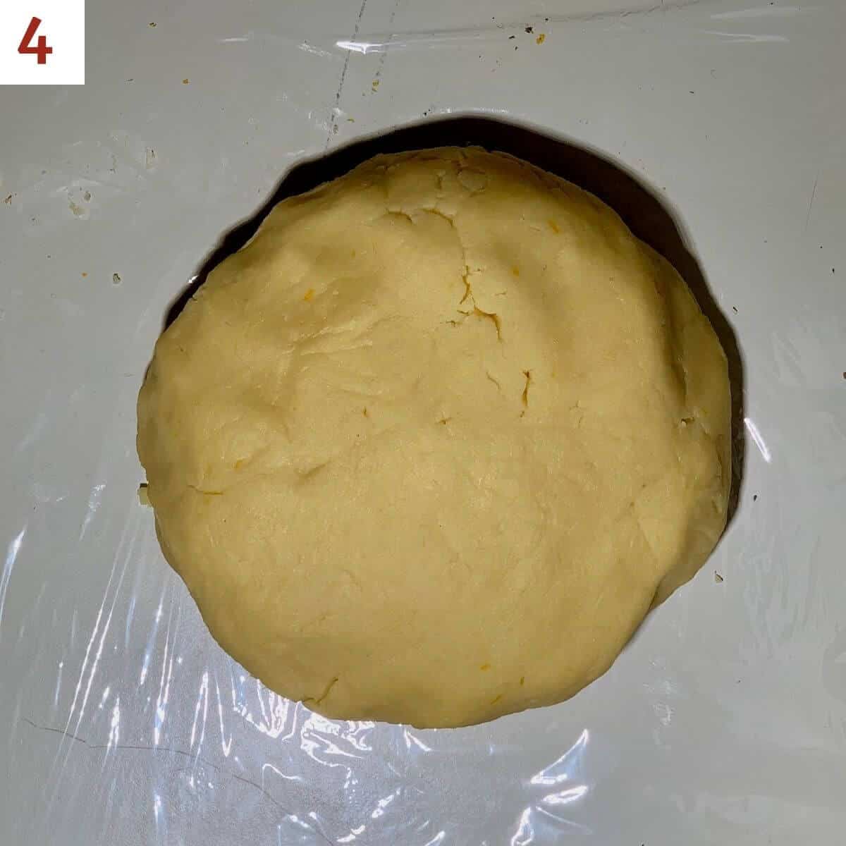 Ball of sugar cookie dough on a white counter.