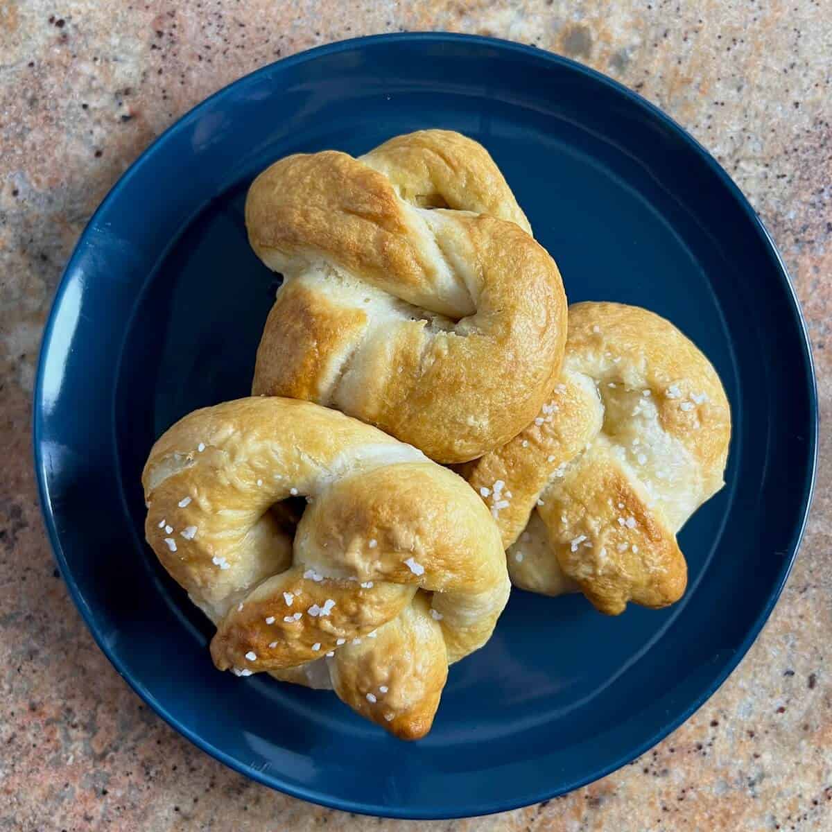 Three pretzels on a blue plate from overhead.