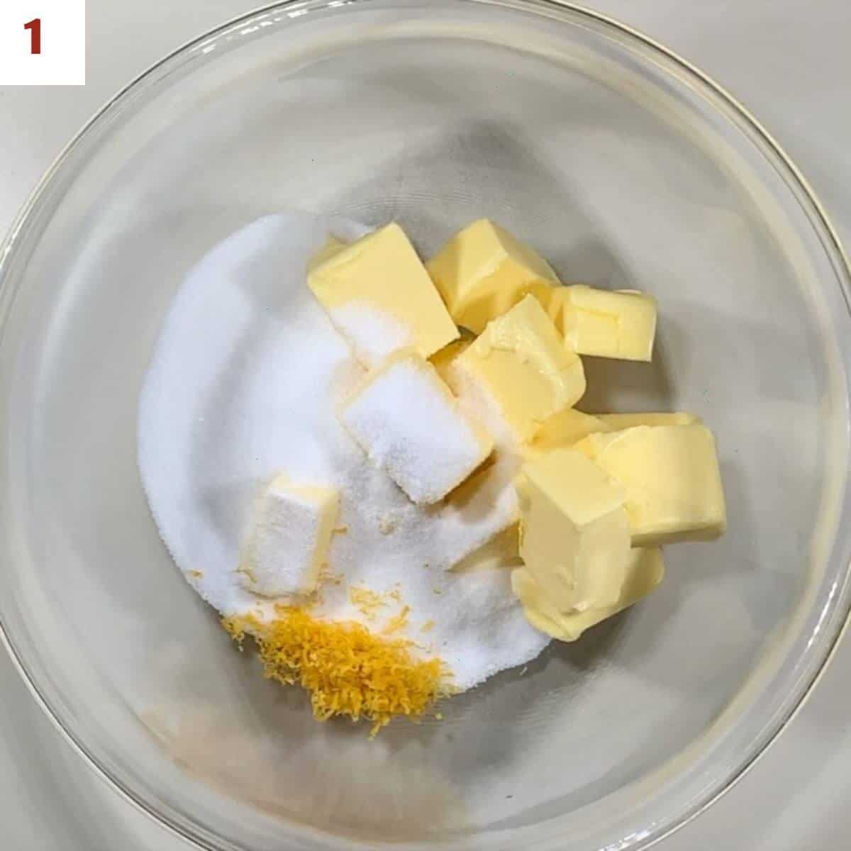 Butter, sugar, & lemon zest in a glass bowl from overhead.