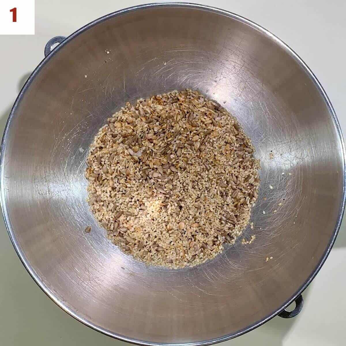 Soaking grains in boiling water in a metal bowl from overhead.