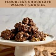 Flourless Chocolate Walnut Cookies piled on a white cake stand Pinterest banner..