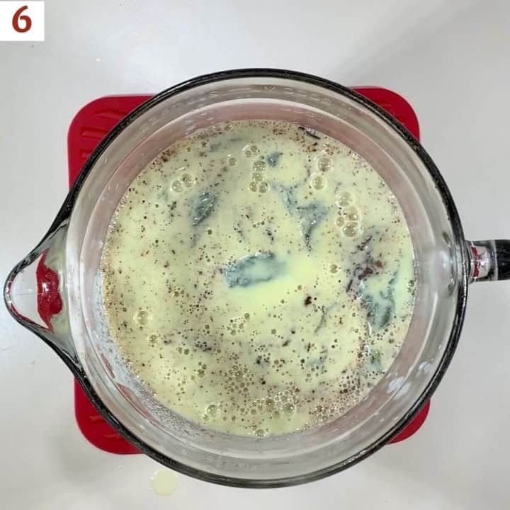 Hot custard & chopped chocolate in a glass bowl.