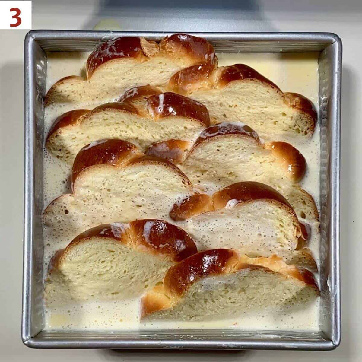 Sliced challah in a pan with custard poured on.