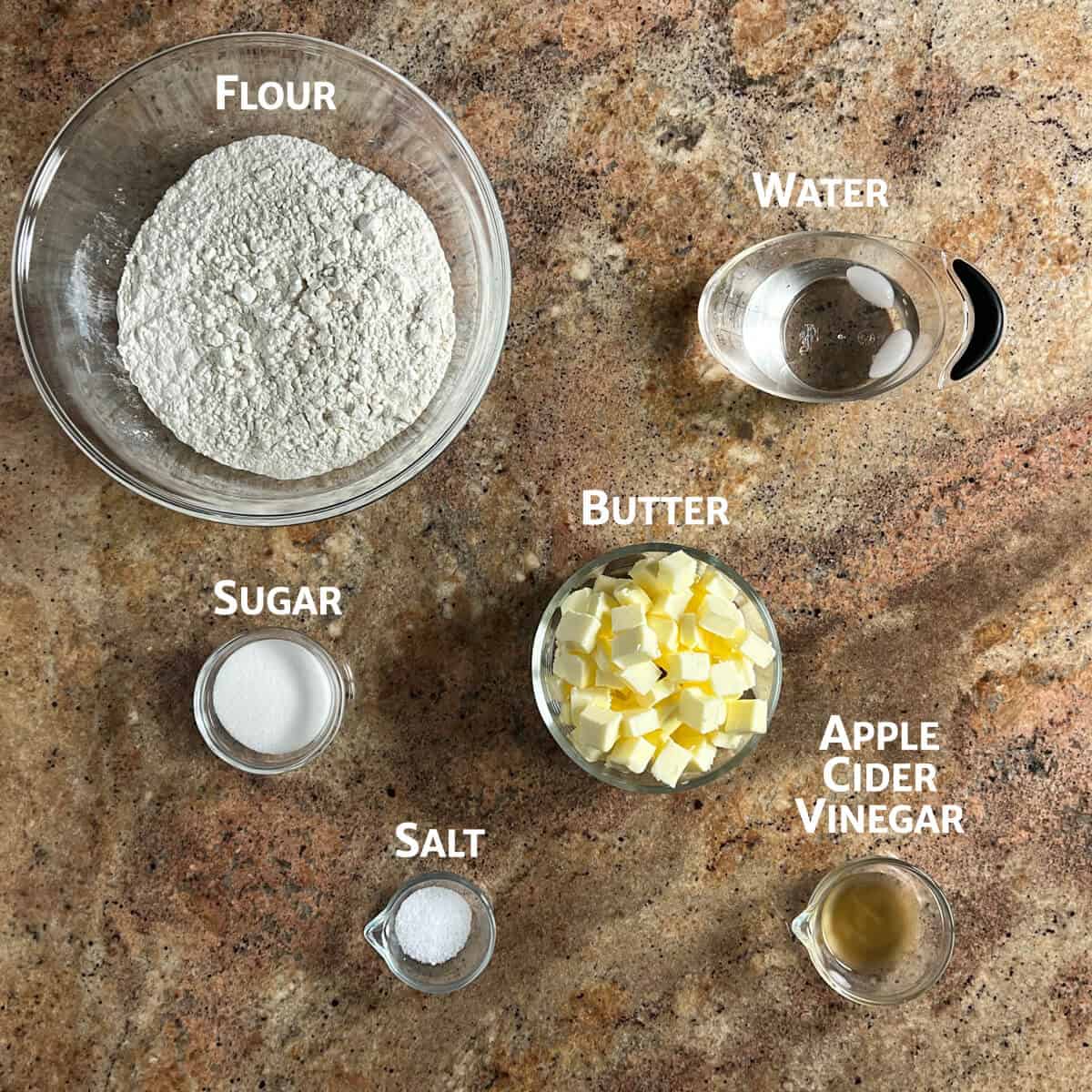 Ingredients for pie crust portioned into glass bowls from overhead.