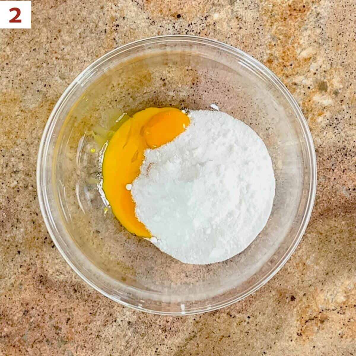 Egg yolks & sugar in a glass bowl from overhead.