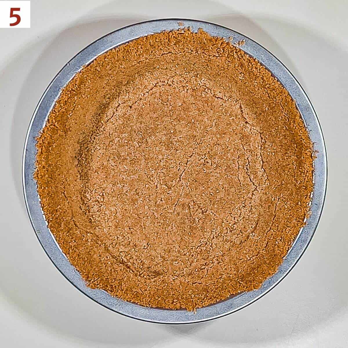 A baked graham cracker crust a 7-inch pie pan from overhead.