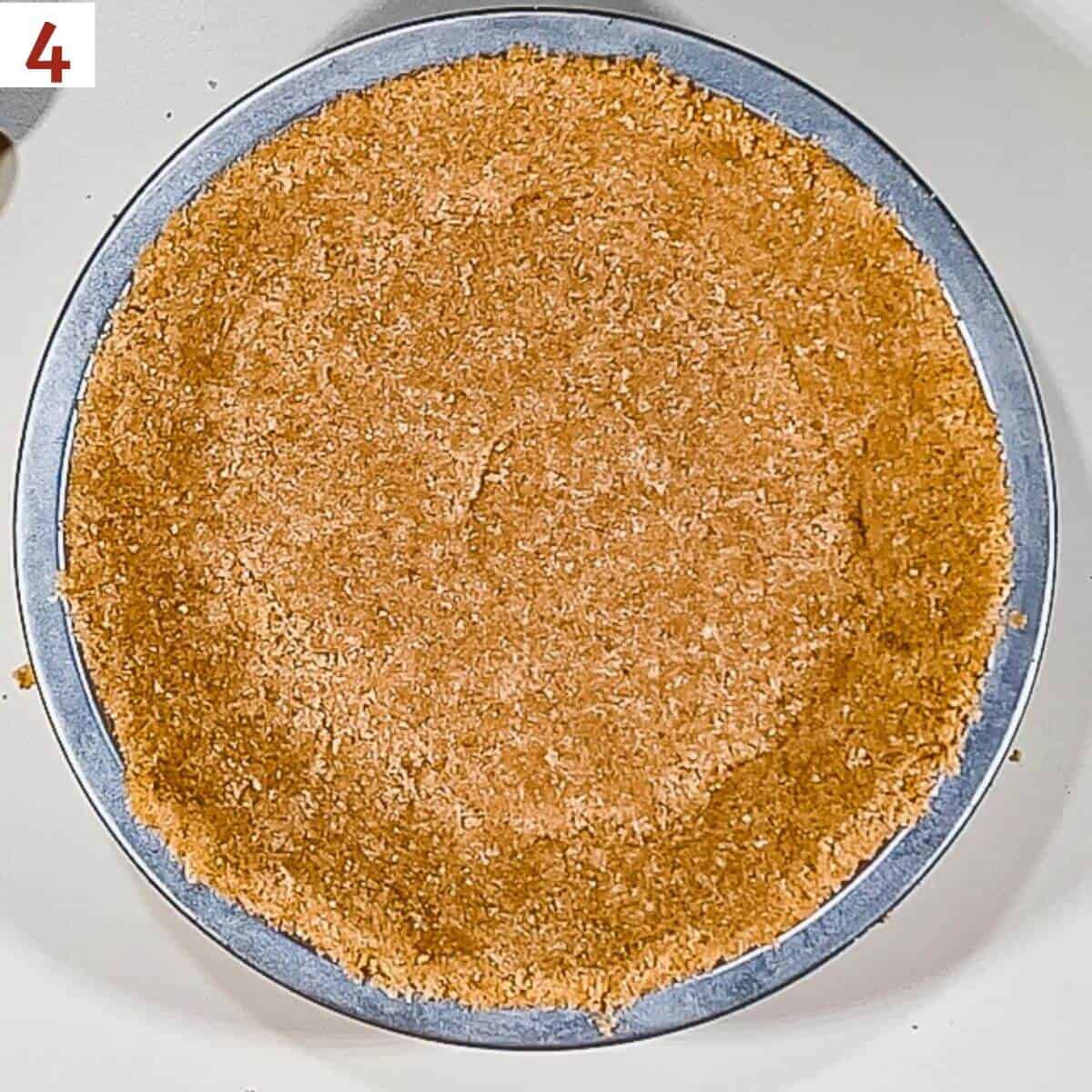 An unbaked graham cracker crust a 7-inch pie pan from overhead.