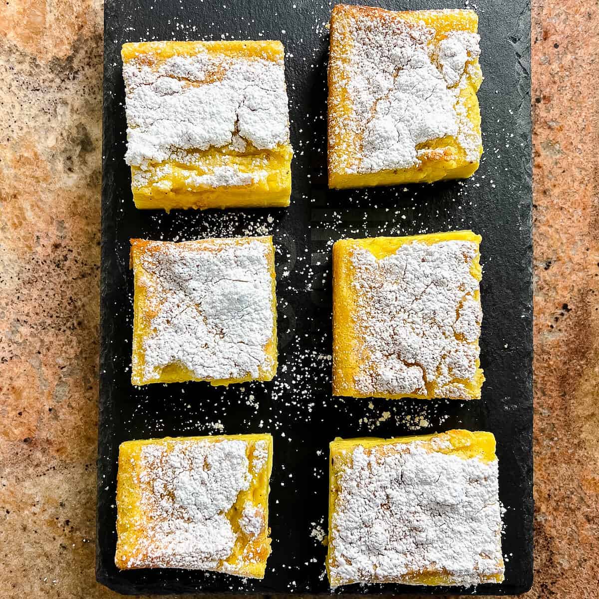 Magic Custard Cake slices on a black slate platter from overhead.