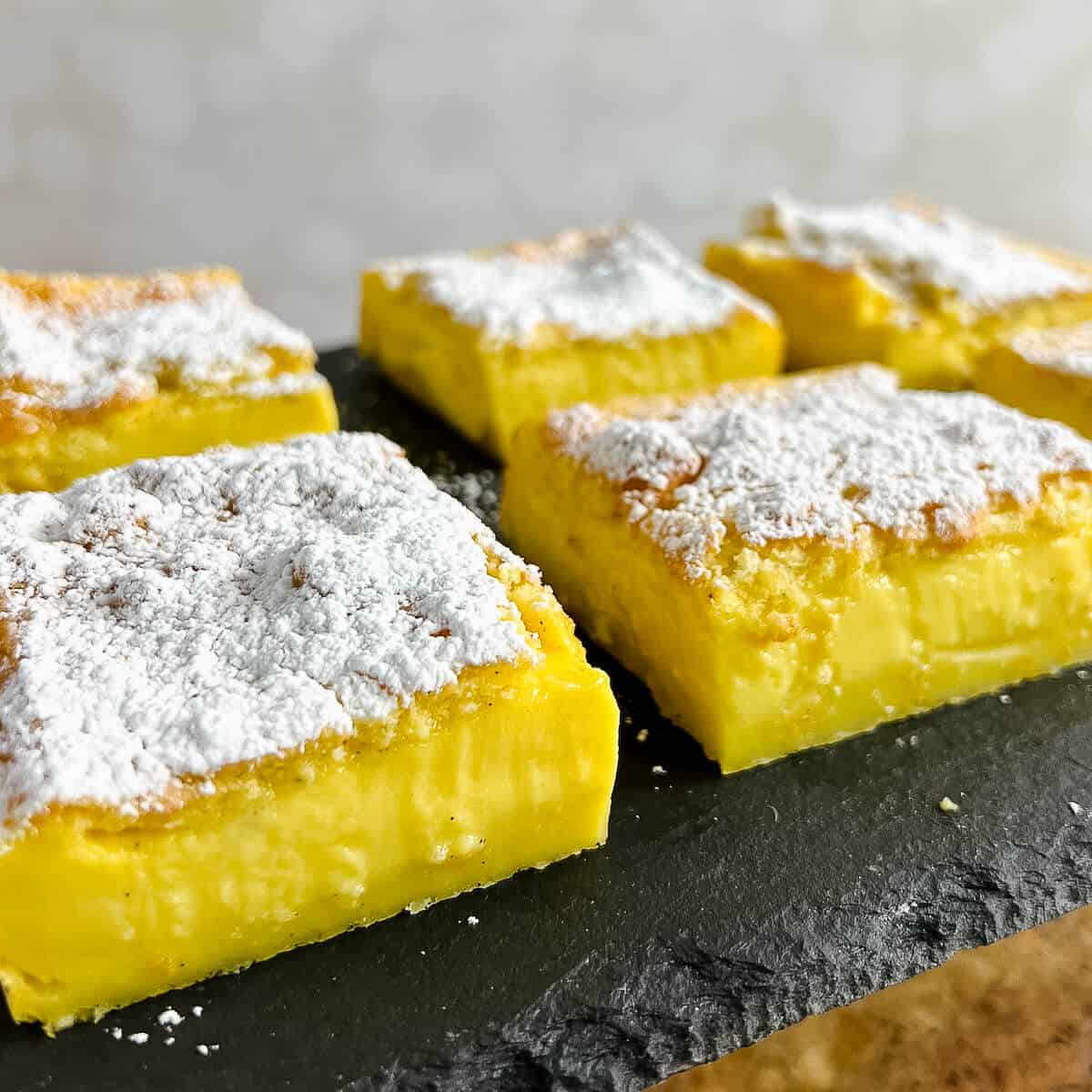 Magic Custard Cake slices on a black slate platter.