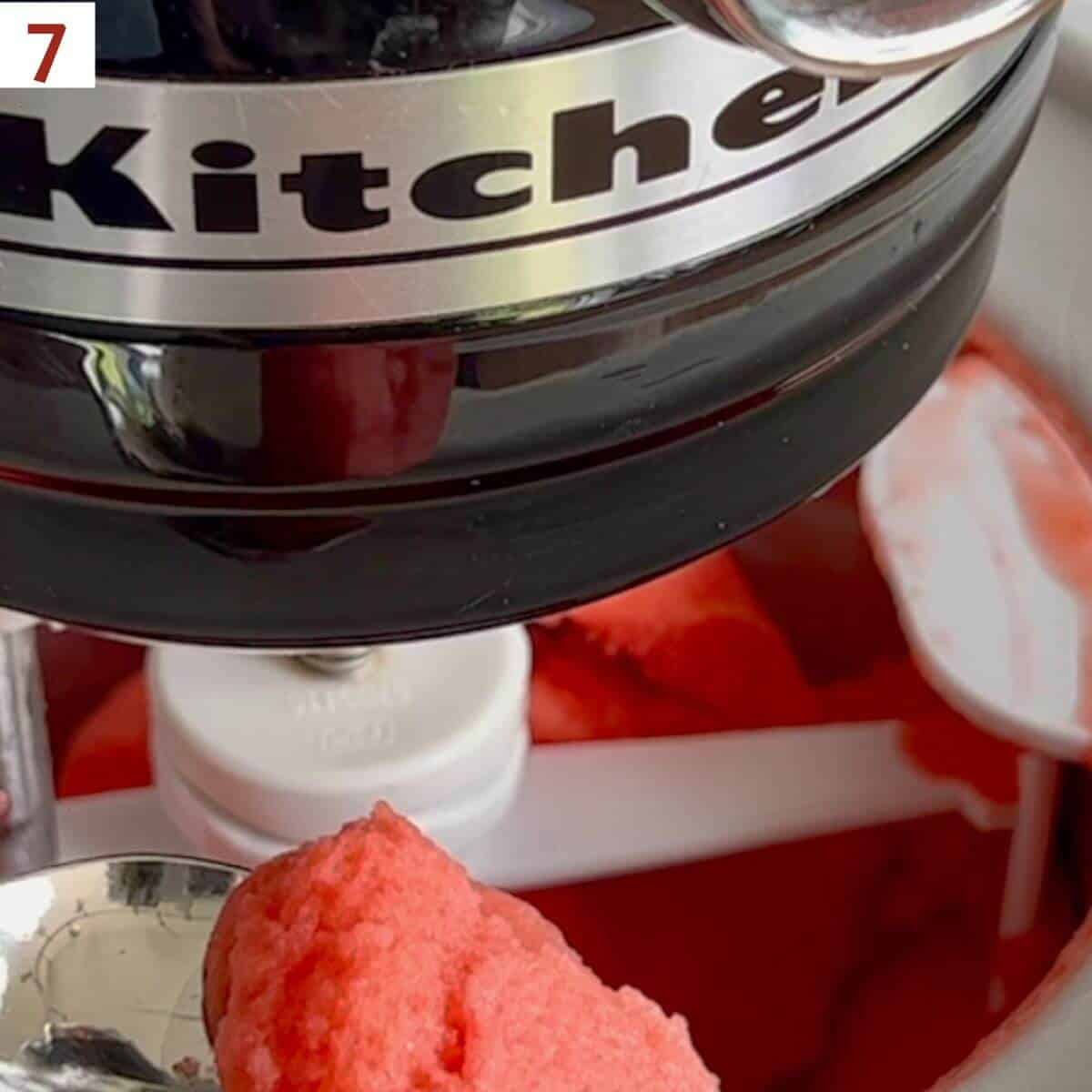 Finished sorbet on a spoon in front of an ice cream maker.