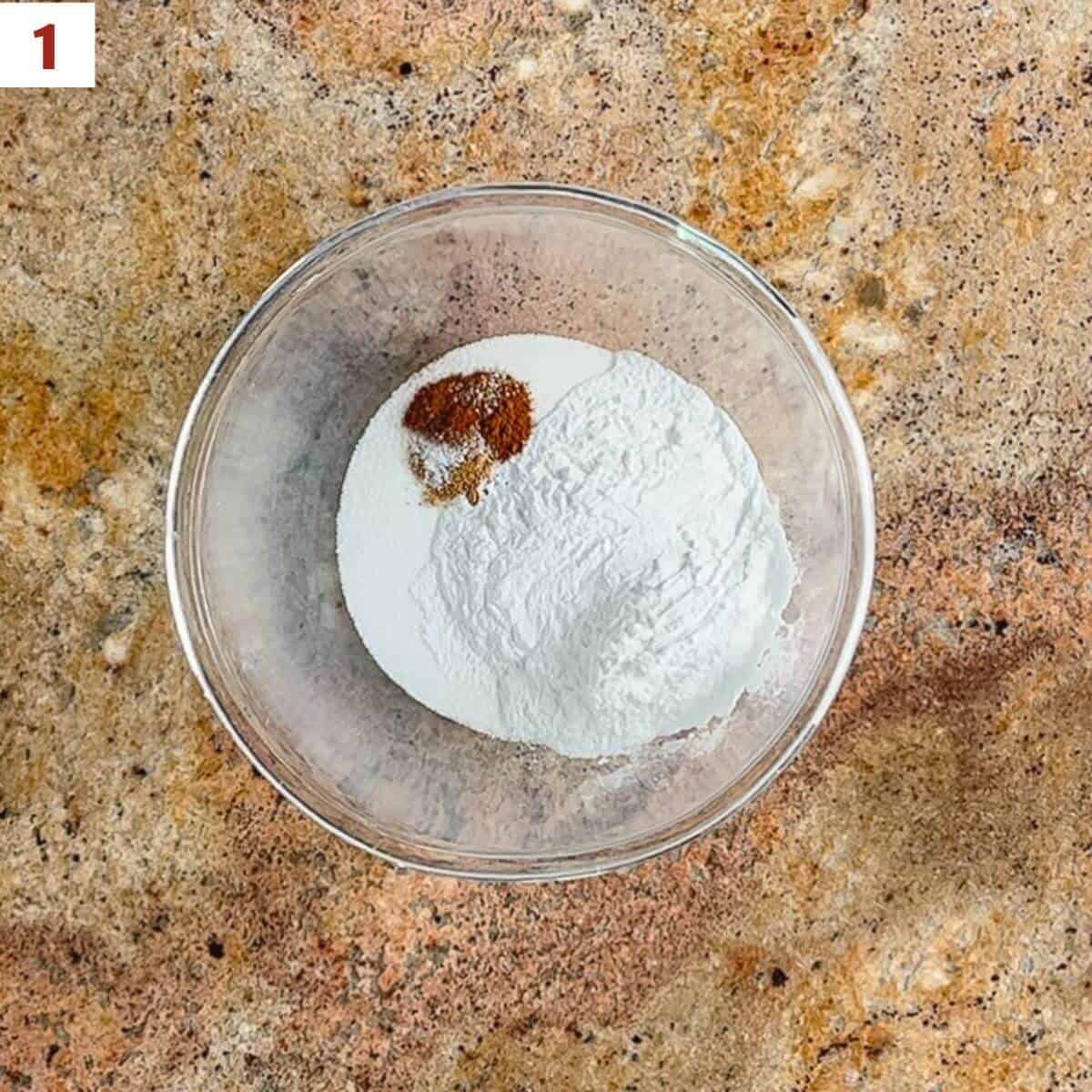 Sugar, Instant ClearJel, cinnamon, nutmeg, and salt in a glass bowl from overhead.