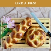 Straight challah on a cutting board with a bread knife and flowers from overhead Pinterest banner.
