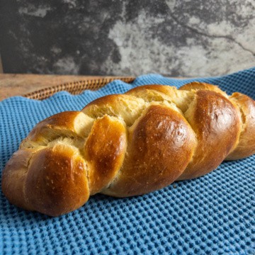 Whole challah loaf on a blue towel.