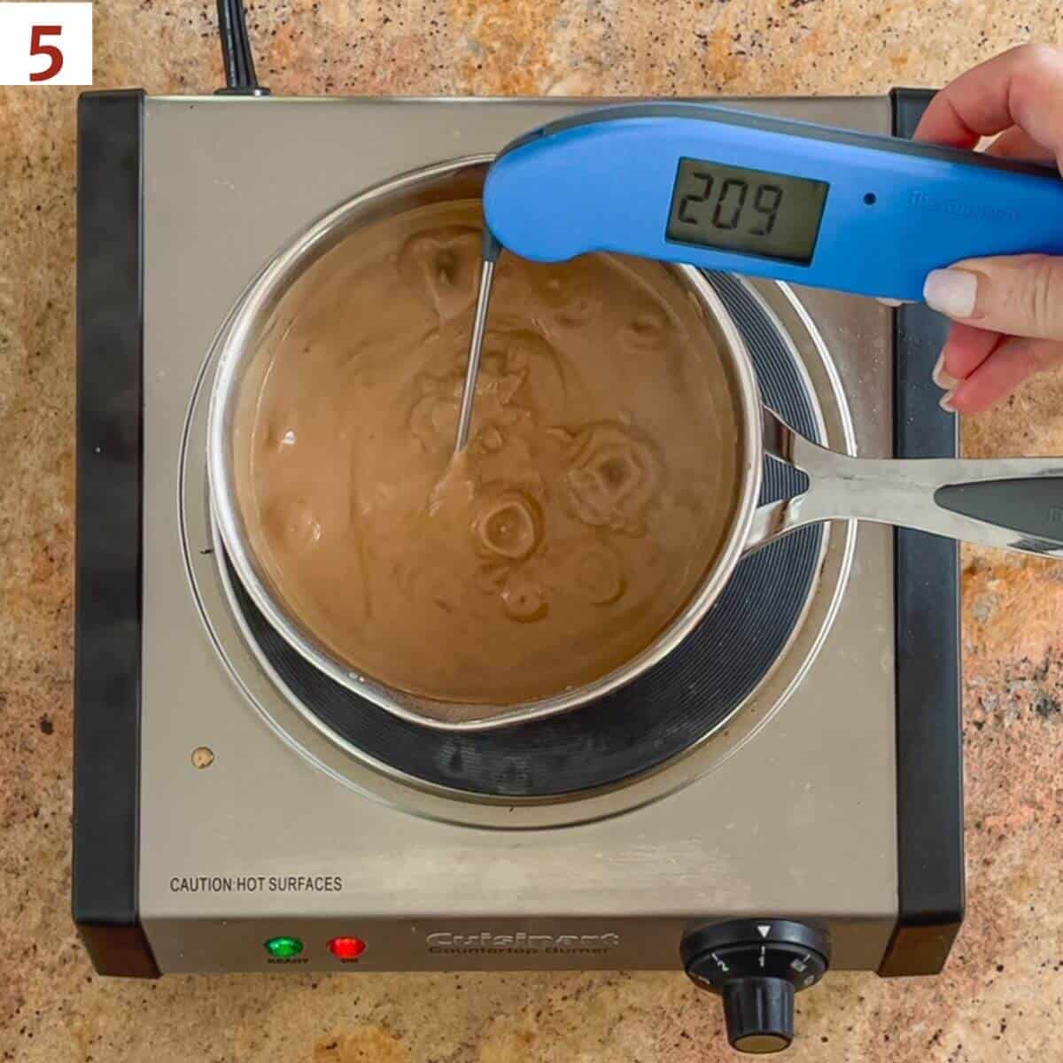 Taking the temperature of cooking chocolate custard with a digital thermometer showing 209˚F.