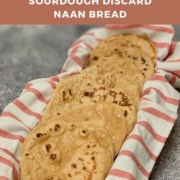 Eight sourdough naan pieces on a red & white striped towel in a basket Pinterest banner.