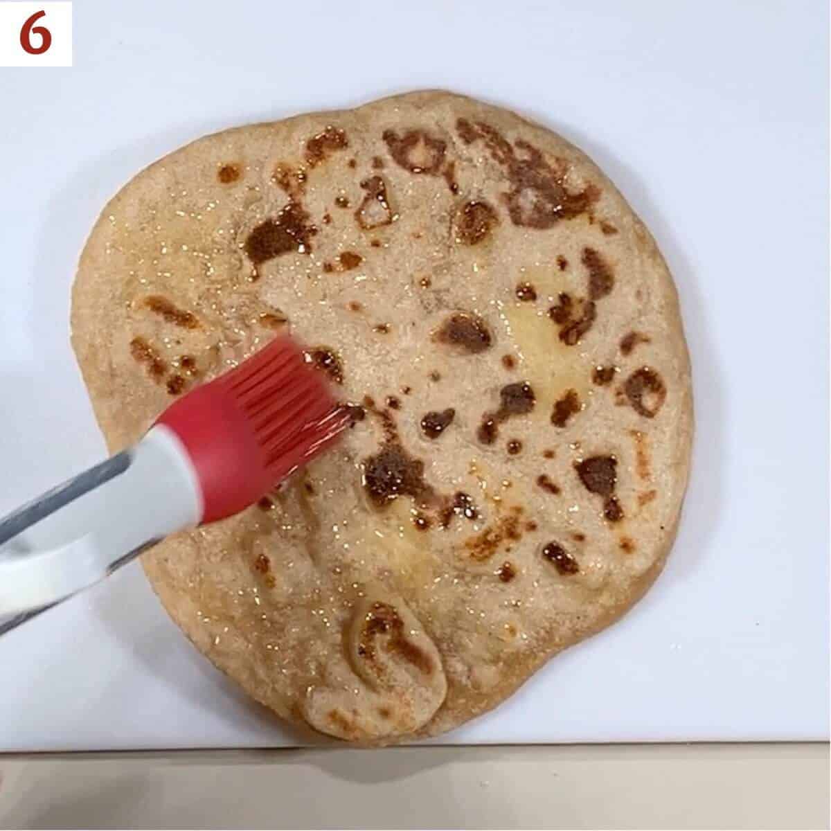 Buttering a whole piece of naan with a pastry brush.