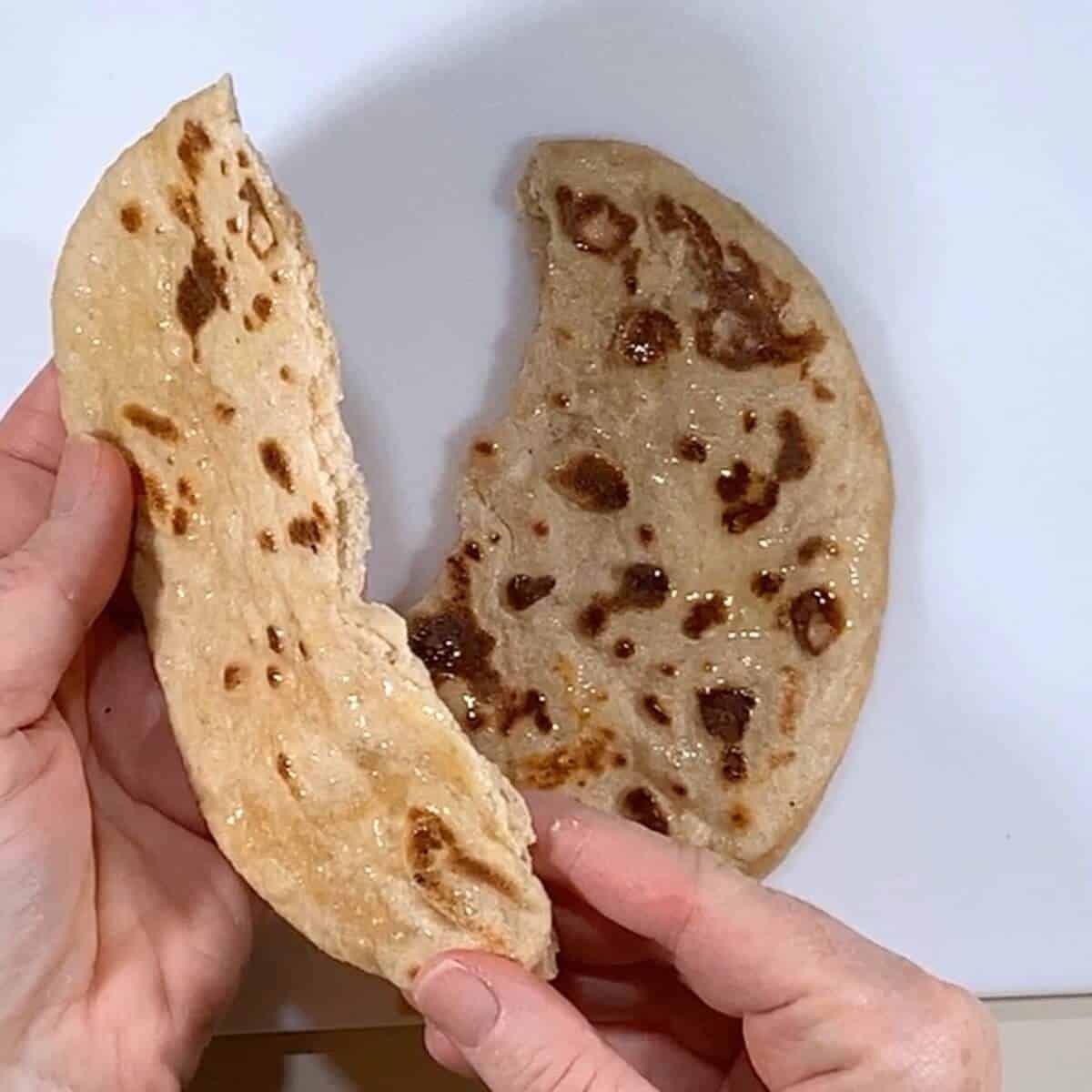 Piece of sourdough naan torn in half.