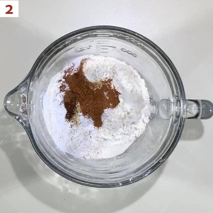 Flour, baking powder, baking soda, cinnamon, ginger, nutmeg, and cloves in a glass bowl.