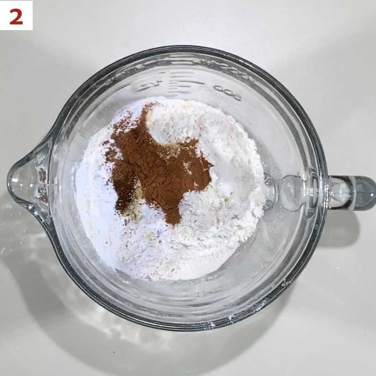Flour, baking powder, baking soda, cinnamon, ginger, nutmeg, and cloves in a glass bowl.