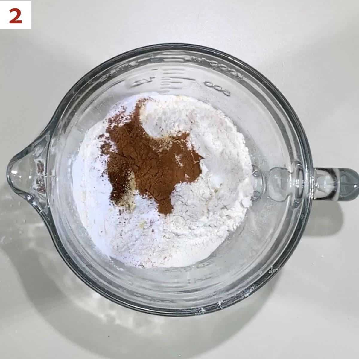 Flour, baking powder, baking soda, cinnamon, ginger, nutmeg, and cloves in a glass bowl.