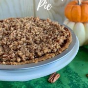 Praline Pumpkin Pie in pie pan with a slice on a white plate next to pumpkin & scattered pecans from overhead Pinterest banner.