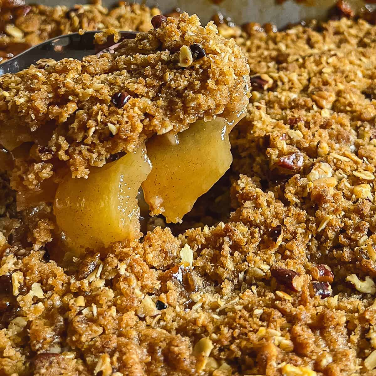 Closeup detail of Apple Crisp being scooped out of the baking pan.