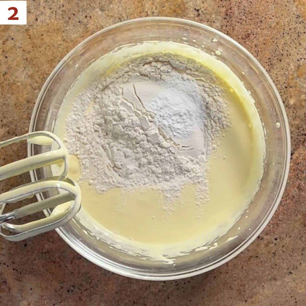 Adding flour, baking powder, and salt to the cake batter.