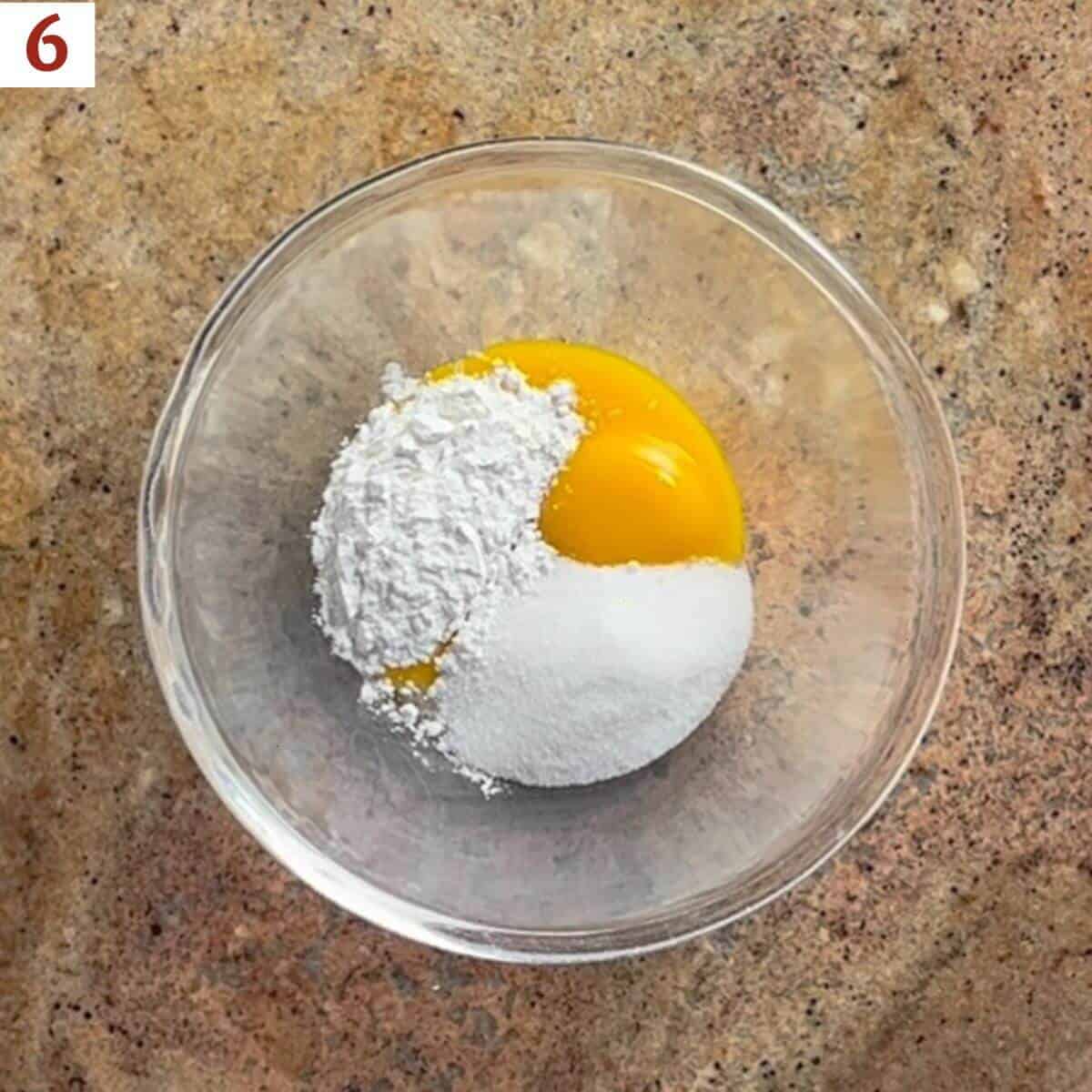 Egg yolks, sugar, and cornstarch in a glass bowl from overhead.