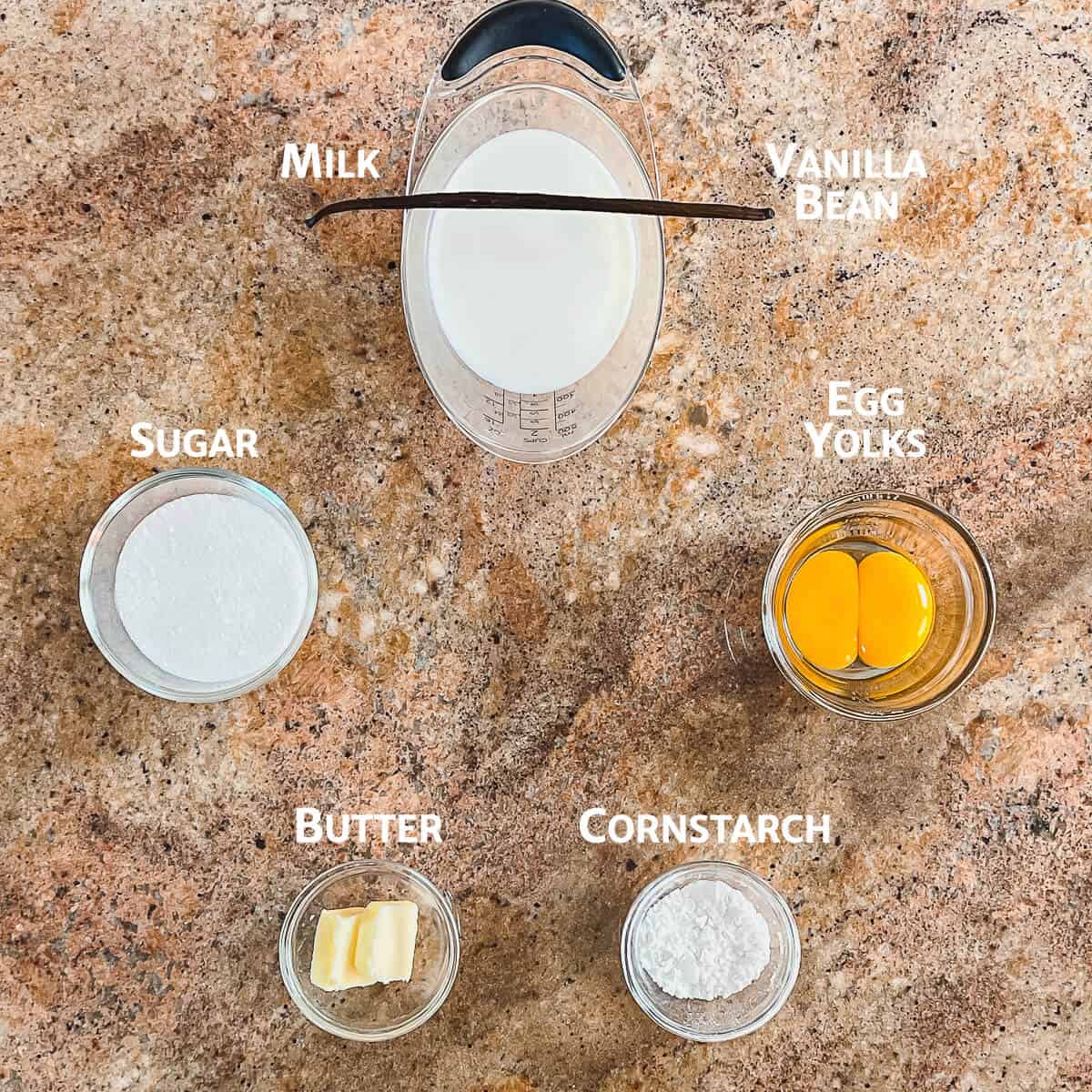 Ingredients for pastry cream portioned into glass bowls from overhead.