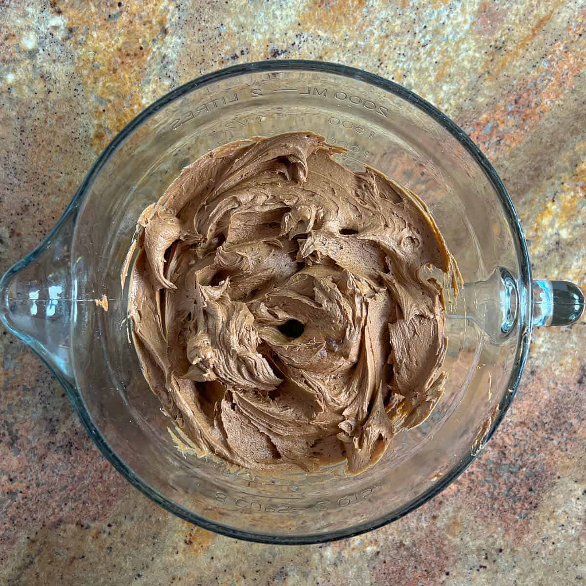 Bowl of dark chocolate buttercream frosting from overhead.