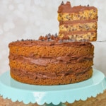 Whole Chocolate Chip Cookie Cake on a blue cake stand with a slice lifted.