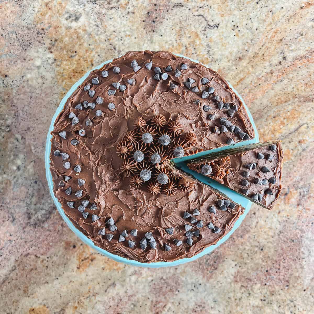 Sliced Chocolate Chip Cookie Cake on a blue cake stand with separate slice from overhead.