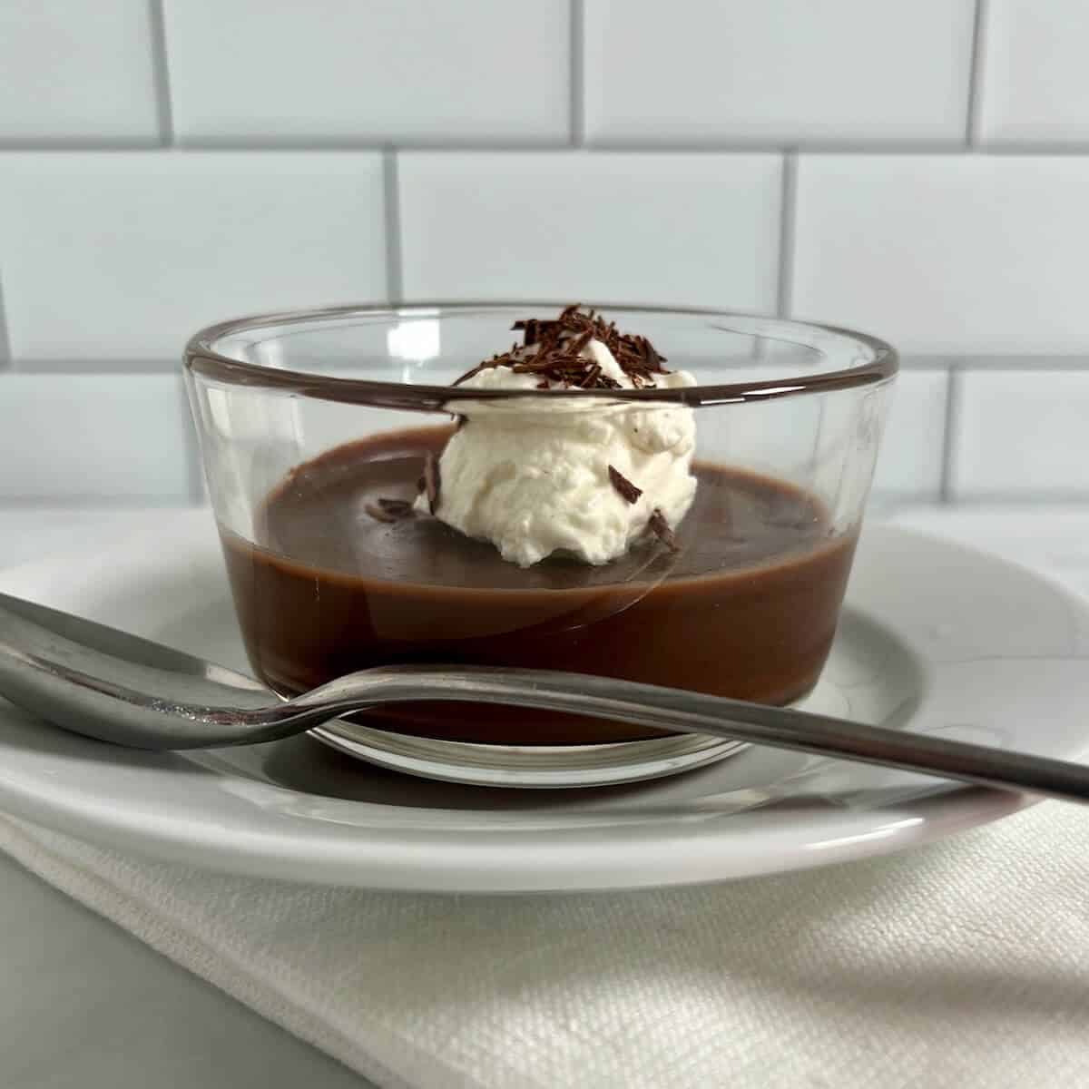 Chocolate pudding garnished with whipped cream and chocolate shavings with a bite taken out.