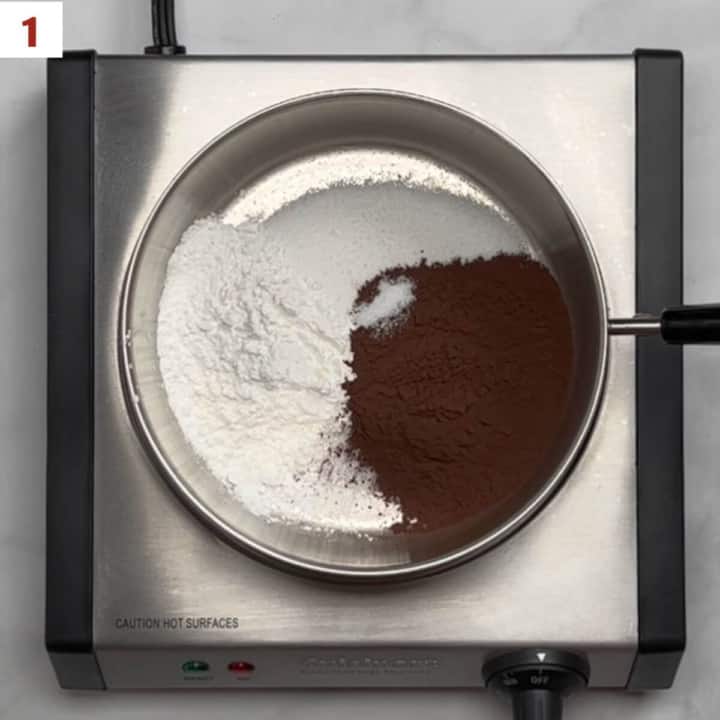 Sugar, cocoa powder, cornstarch, and salt in a saucepan on a hot plate from overhead.