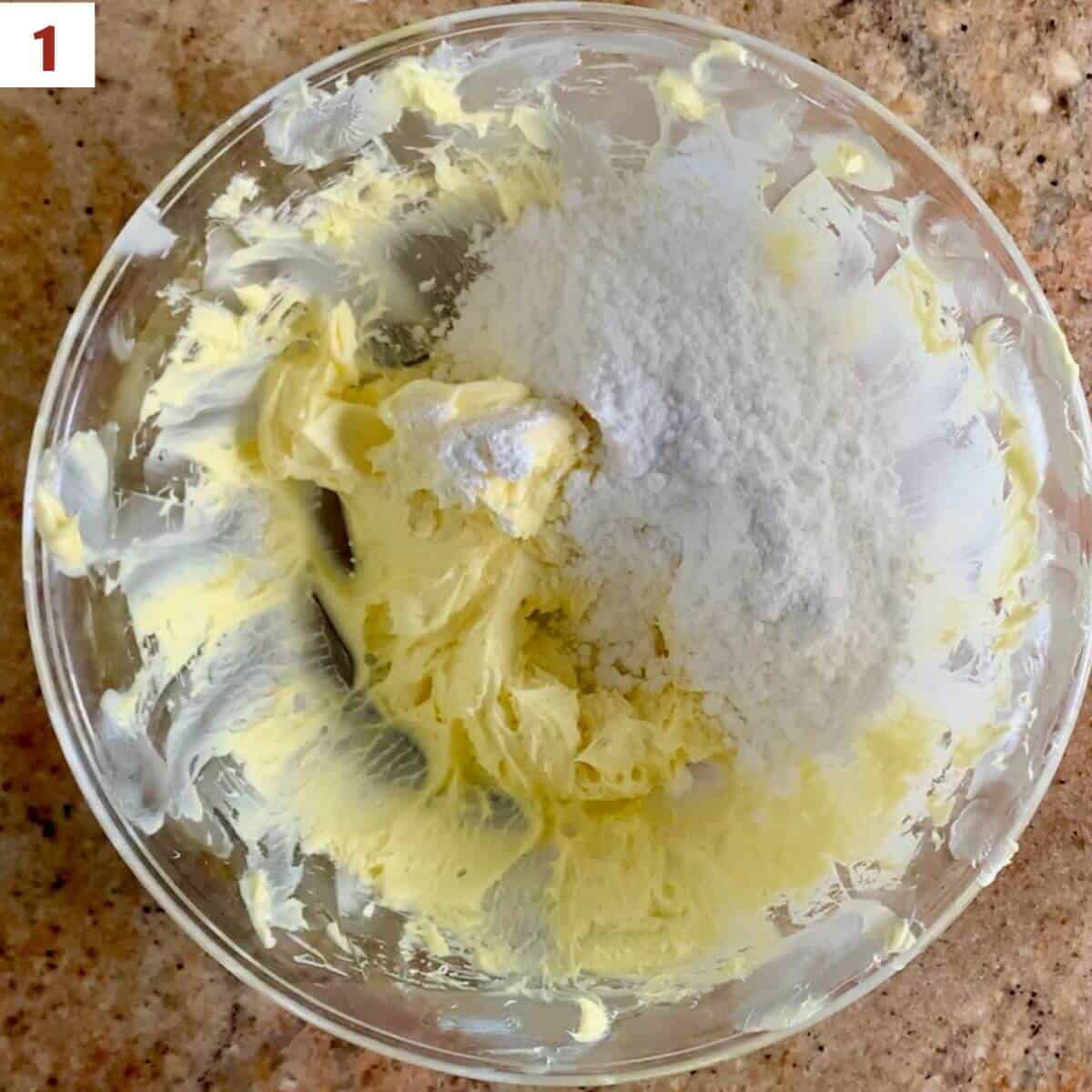 Adding flour to cookie dough in a glass bowl.