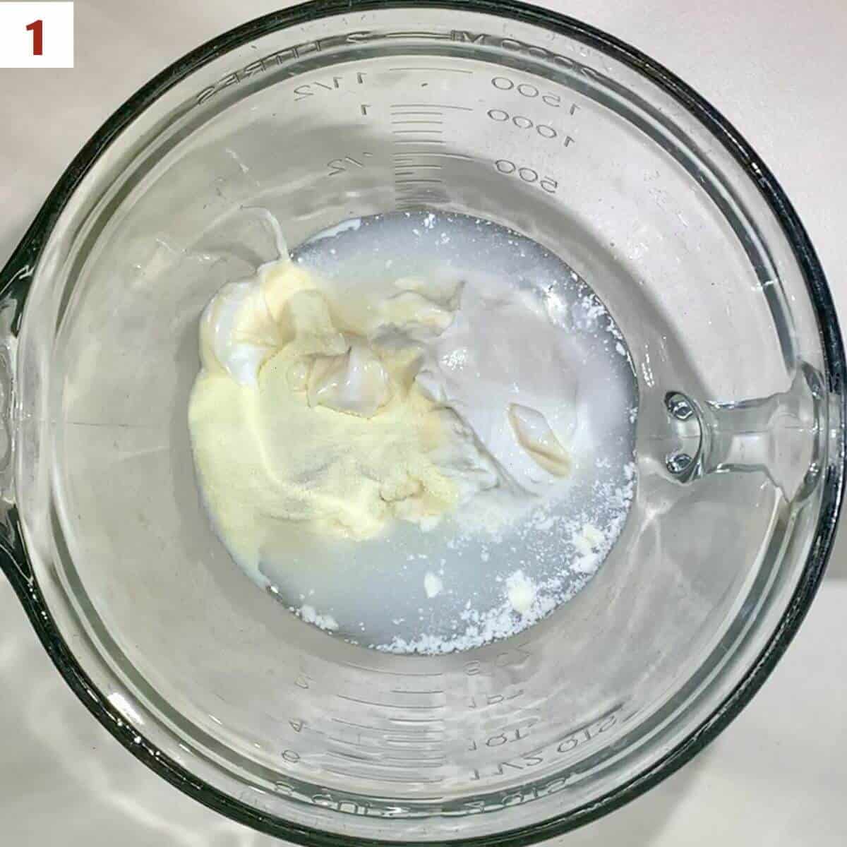 Sour cream, mayonnaise, water, and buttermilk powder in a glass bowl from overhead.